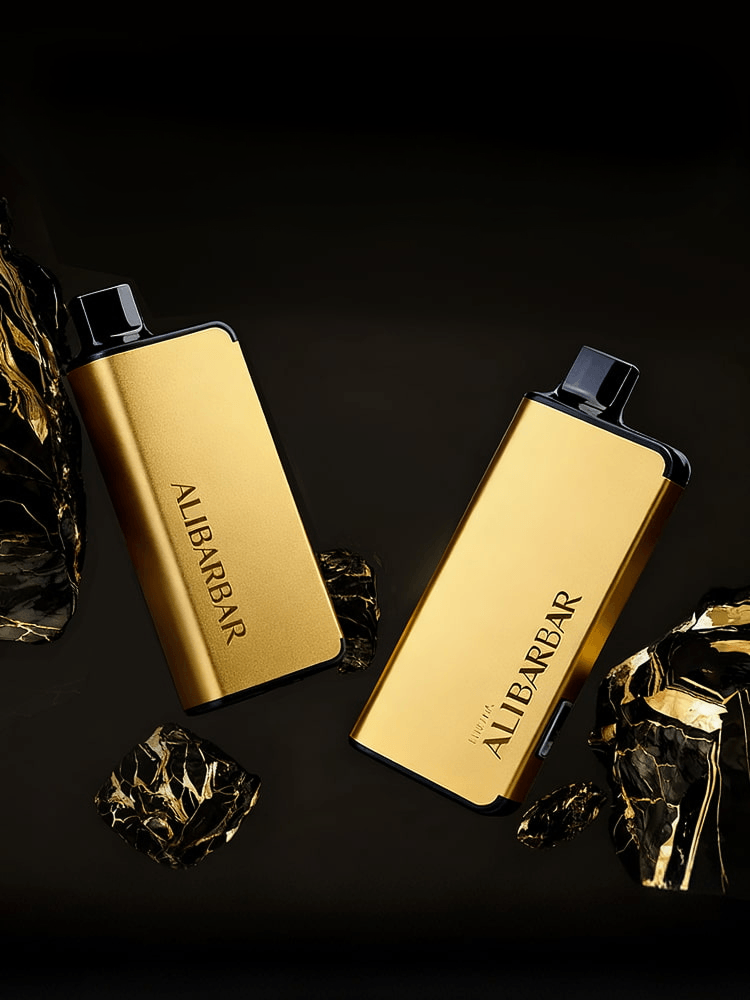 Two metallic gold Alibarbar disposable vape devices on a black marble background